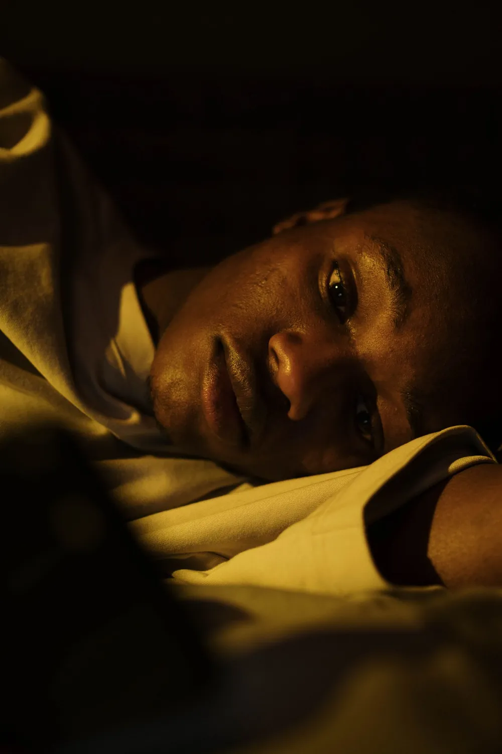 Man lying awake at night with a racing heart after waking up sweating